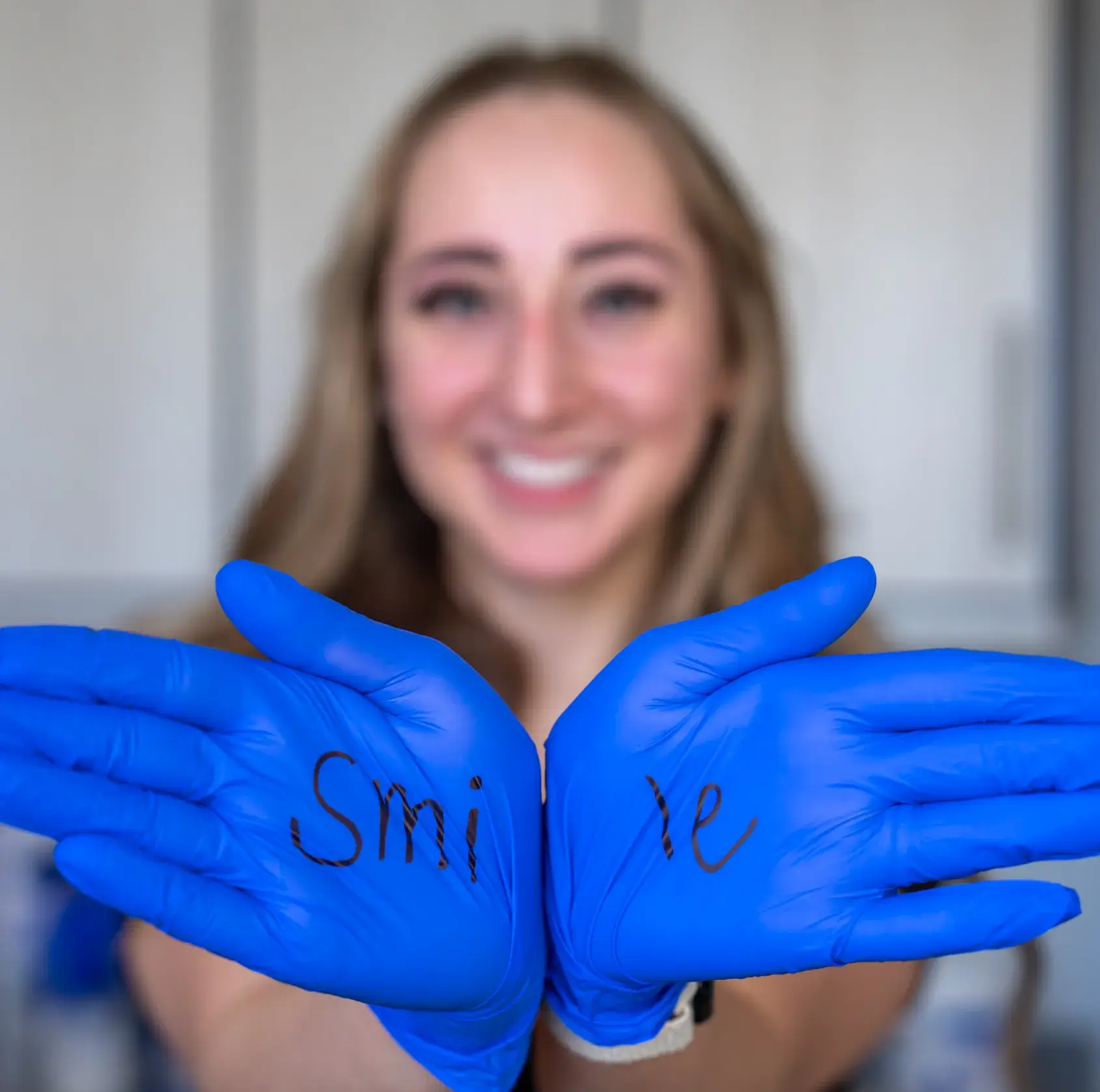 Lächelnder Zahnarzt mit blauen Handschuhen